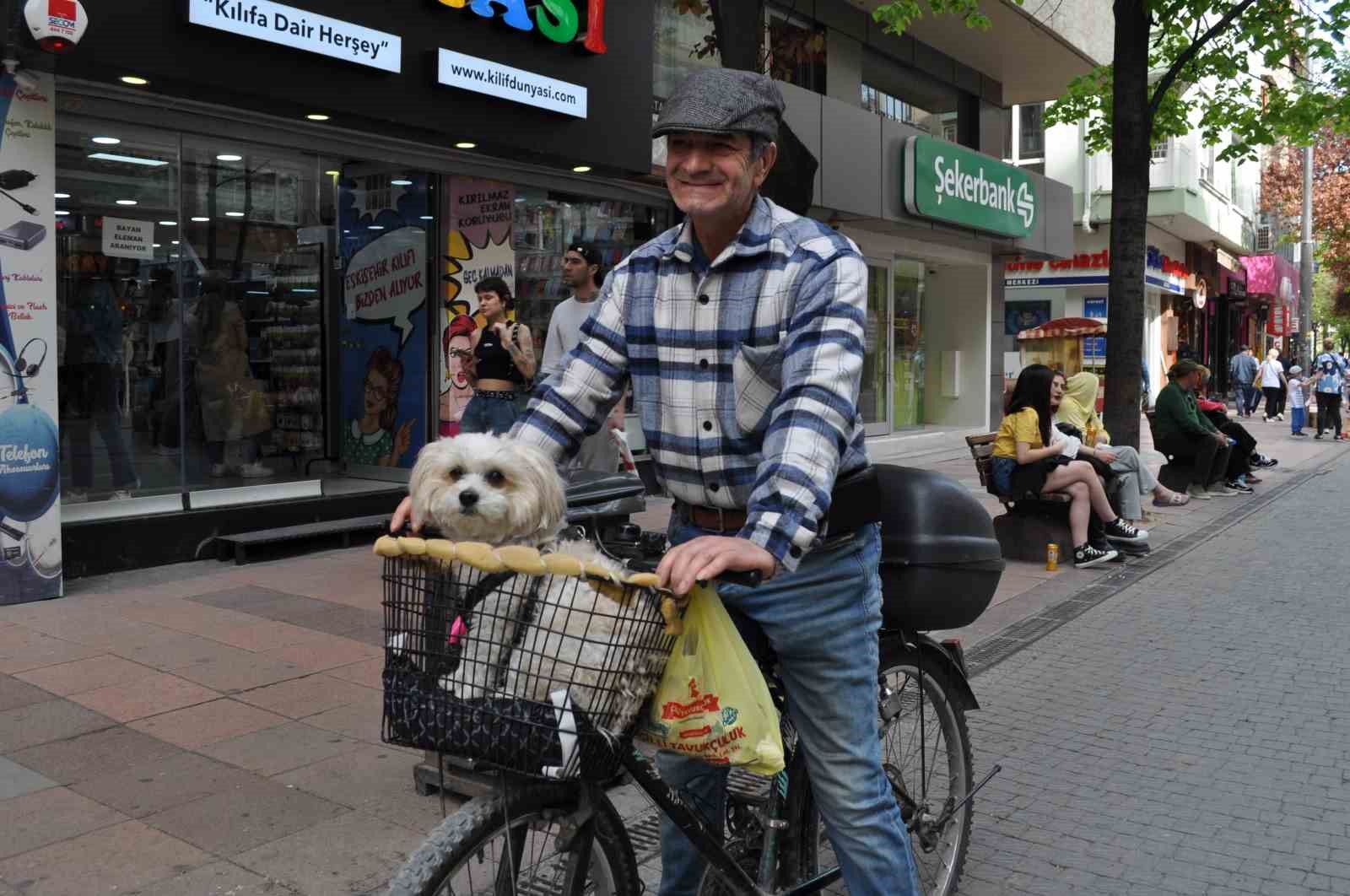 Köpeğini bisikletinin sepetine koyup güzel havanın tadını çıkardı
