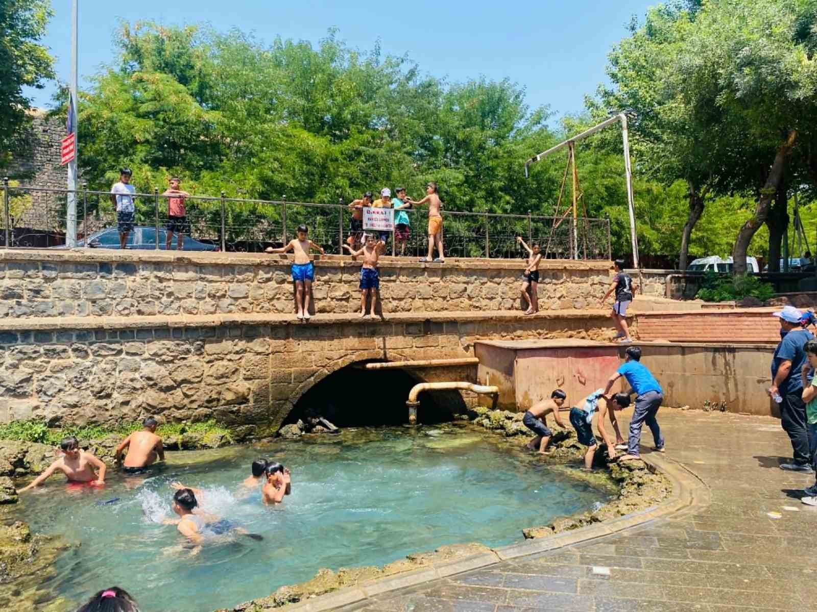 Diyarbakır’da çocuklar ailelerinin nezaretinde süs havuzunda serinliyor
