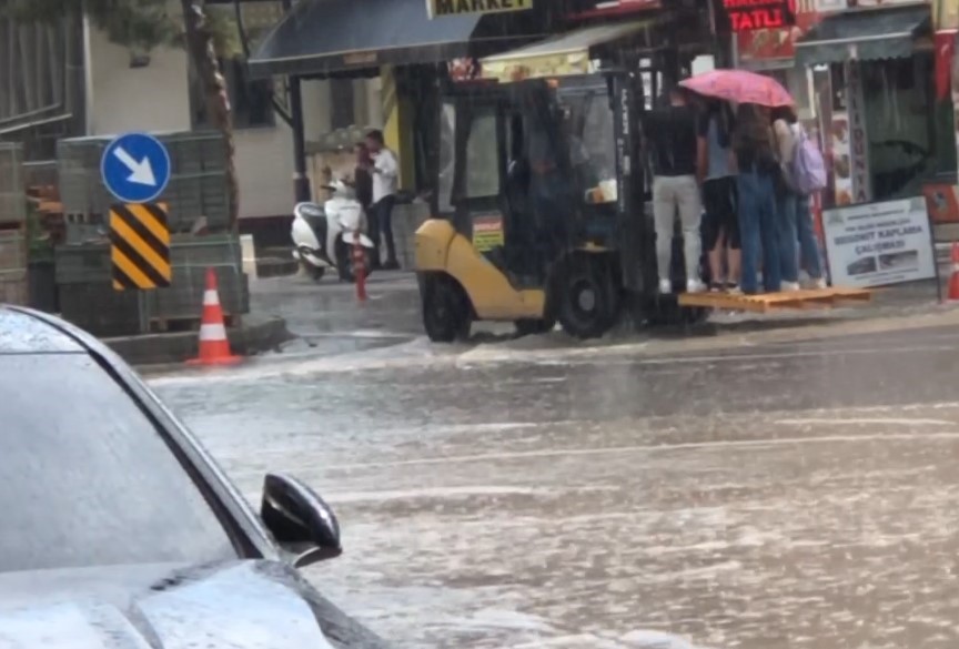 Aniden başlayan yağış sonrası yayaların imdadına belediye forkliftle yetişti
