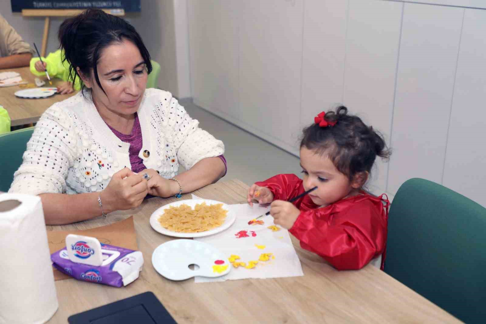 Büyükşehir oyuncak kütüphanesinde, anne ve çocuklar birlikte eğleniyor
