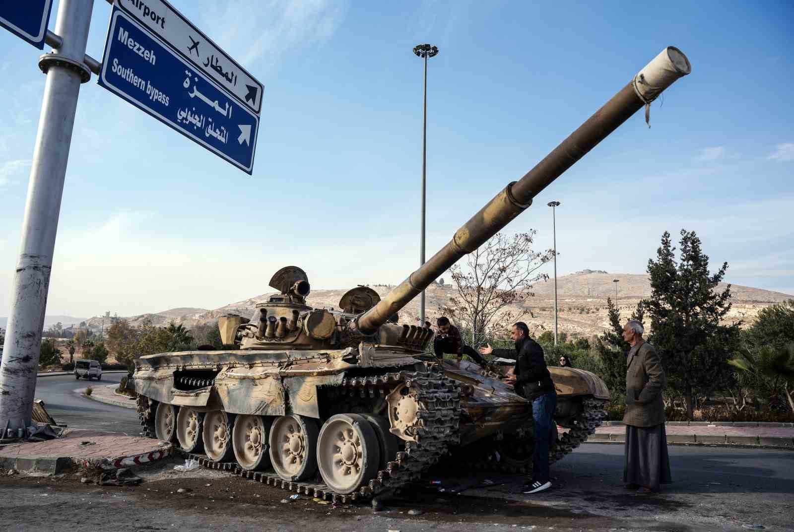 Suriyelilerden Esad rejiminden geriye kalan tankların üzerinde “zafer” pozu
